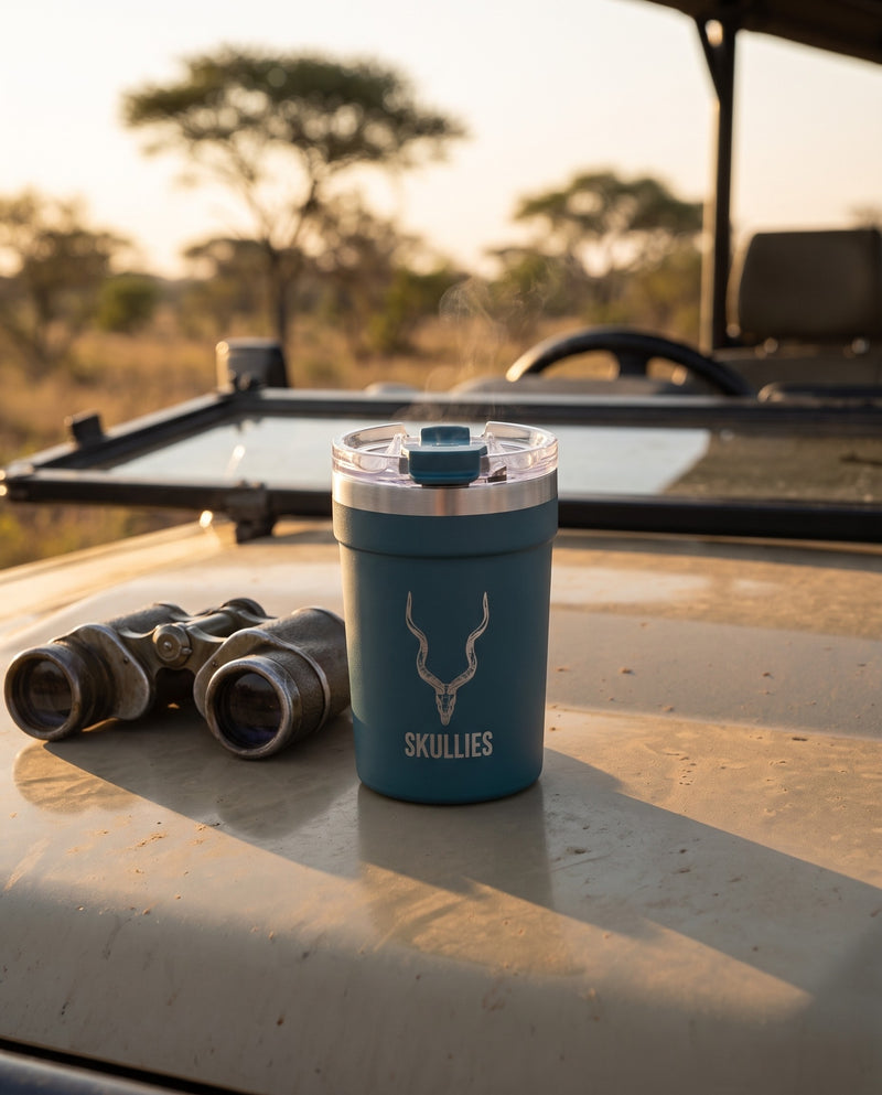 Load image into Gallery viewer, Green Kudu Skullies Coffee Cup on a safari vehicle bonnet at sunrise
