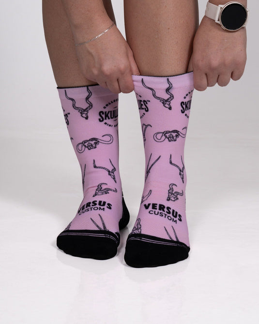 Front view of pink Skullies crew socks with kudu, buffalo and gemsbok skull line drawings